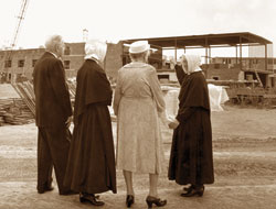 In this file photo published in The Criterion on Aug. 19, 1966, Mother Marie Mathilde, far right, superior of the Little Sisters of the Poor in Indianapolis, shows her assistant and two guests how much progress has been made on construction of the new St. Augustine Home for the Aged at 2345 W. 86th St. The home was built with donations from more than 18,000 individuals, families, 
        businesses and foundations.