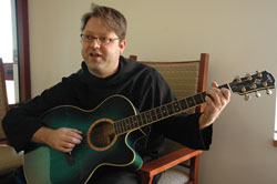 Benedictine Brother Christian Raab plays his guitar on Jan. 2 at Saint Meinrad&rsquo;s new guest house. He enjoys community prayers, music, Mass, reading and silence, which he describes as &ldquo;a matter of times and places&rdquo; in monastic life.