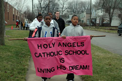 Holy Angels sixth-graders Charles Davis, left, and Desmond Huskie carry a banner on Jan. 12 during the school&rsquo;s annual march honoring the life and ministry of Dr. Martin Luther King Jr. Students from St. Anthony School also participated in the march and memorial Mass.