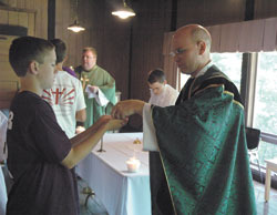 Grady Gaynor, a member of Our Lady of Mount Carmel Parish in Carmel, Ind., in the Lafayette Diocese, receives Communion from Father Robert Hausladen on June 15, 2006, during the first Bishop Brut&eacute; Days held at Bradford Woods Retreat Center near Martinsville.