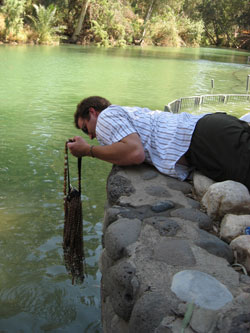 Adam Boyden dips his rosaries into the&nbsp;Jordan&nbsp;River, the site of Jesus&rsquo; baptism. Many young adults placed objects into the river to take back for family and friends. 