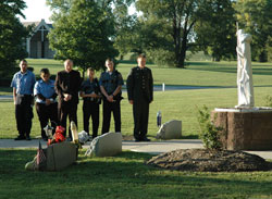 Father Steven Schwab, third from left, pastor of St. Thomas Aquinas Parish in Indianapolis and Catholic chaplain of the Indianapolis Metropolitan Police Department, prays with emergency medical technicians, firefighters, police officers and military personnel during the playing of &ldquo;Taps&rdquo; at the fifth annual archdiocesan Blue Mass on Sept. 11 at Calvary Cemetery in Indianapolis.