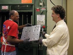 Instead of throwing away old computers, some Catholic schools and parishes in the archdiocese have turned to RecycleForce, an Indianapolis company that recycles parts from old electronic equipment and employs people just released from prison to do the work. Here, employee John Hill takes a computer shell from the company&rsquo;s president, Thomas Gray.