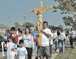 St. Mary parishioner Roberto Aguayo of Indianapolis carries a large wooden crucifix and leads pro-life supporters along West 86th Street in Indianapolis on Sept. 23 while his wife, Patricia, in the ninth month of her pregnancy, walks beside him with their children, Roberto, Andrea and Ricardo. The Aguayos&rsquo; baby, Rolando, was born on Sept. 29. Dozens of pro-life supporters prayed the rosary for an end to abortion during the two-mile march to the Planned Parenthood center for a prayer vigil.