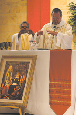 Archbishop Daniel M. Buechlein and Father Varghese Maliakkal, administrator of St. Michael the Archangel Parish, consecrate the Eucharist during a Sept. 29 feast&nbsp;day Mass at the Indianapolis West Deanery church. A nine-day novena preceded the liturgy. The portrait depicting St.&nbsp;Theodora Gu&eacute;rin teaching children will hang on a pillar in the church.	