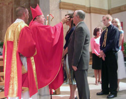 Archbishop Daniel M. Buechlein anoints Cassie Caccavo while her sponsor, Jim Clark, stands by her during the sacrament of confirmation at SS. Peter and Paul Cathedral in Indianapolis. Cassie and Clark are members of St.&nbsp;Simon the Apostle Parish in Indianapolis. (Submitted photo) 