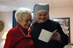 Sister Margaret Banar, a member of the international Little Sisters of the Poor order, looks at photographs with St. Augustine Home for the Aged resident Beatrice Spurgeon of Indianapolis. Sister Margaret said her habit &ldquo;opens doors&rdquo; that otherwise would not be accessible in her ministry. (Photo by Mary Ann Wyand) 