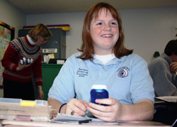 Alyssa Hendershot, a sophomore at Our Lady of Providence Jr./Sr. High School in Clarksville, holds a wireless device commonly known as a clicker that allows her to interact with classroom lectures and take tests. It is an element of SMART technology in four classrooms at Providence. Alyssa&rsquo;s science teacher, Virginia Shirley, stands in the background and holds several more clickers. (Submitted photo) 