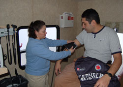 Medical assistant Alma Banegas, left, prepares to take the blood pressure of Francisco Ruiz inside the mobile van of the Gennesaret Free Clinics. The van visits St. Mary Parish in Indianapolis every Saturday to provide medical care to Hispanic immigrants and parishioners. Banegas and Ruiz are members of St.&nbsp;Mary Parish. (Submitted photo)	