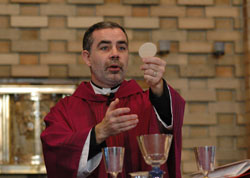 Father Joseph Moriarty elevates the Eucharist during a Feb. 11 Mass at the Our Lady of Fatima Retreat House chapel in Indianapolis on the feast of Our Lady of Lourdes and in observance of the World Day of the Sick. The Mass was also celebrated for the intention of Archbishop Daniel M. Buechlein, who is undergoing chemotherapy treatments for Hodgkin&rsquo;s lymphoma. The day of reflection included instructions on the Spiritual Exercises of St. Ignatius of Loyola. (Photo by Mary Ann Wyand)	