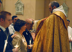 Benedictine Father Julian Peters, administrator pro-tem of SS. Peter and Paul Cathedral Parish in Indianapolis, lays his hands on the head of Russell Jenkins in a celebration of the rite of confirmation during Cathedral Parish&rsquo;s Easter Vigil on March 22. Jenkins and his wife, Linda, second from left, were received into the full communion of the Church during the liturgy at which their son, transitional Deacon Aaron Jenkins, assisted Father Julian. Russell and Linda Jenkins are members of St. Mary Parish in Rushville. (Photo by Sean Gallagher) 