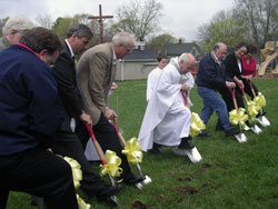 St. Joseph parishioners join Father Daniel Atkins, pastor, at the groundbreaking for a long-awaited parish hall in Corydon on April 13. The group who broke ground included project manager Joe&nbsp;Shireman, left; architect Larry Timperman (hidden); fundraising committee members Ron&nbsp;Casabella and Mike Bennett; Father Atkins; parish finance chairman Ed Hoehn; parish council president Teresa&nbsp;King; and Heidi Imberi, the principal of St. Joseph School. (Photo by Patricia Happel Cornwell) 