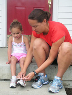 Laura Phillips, right, laces up her 3-year-old daughter Kate&rsquo;s shoes as they prepare for a run around their Indianapolis neighborhood. (Photo by John Shaughnessy)