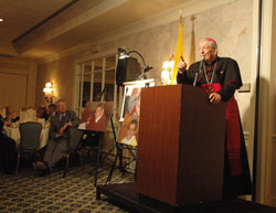 Archbishop Pietro Sambi, apostolic nuncio to the United&nbsp;States, speaks on May&nbsp;3 at the Meridian Hills Country Club in Indianapolis during a fundraising dinner sponsored by the Franciscan Foundation for the Holy Land. The dinner supported the Franciscan Boys Home in Bethlehem. Photos of the home&rsquo;s residents are displayed next to Archbishop Sambi. (Photo by Sean Gallagher)