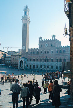 Tourists and townspeople gather at Siena&rsquo;s Piazza del Campo, where its famous horse race, the Palio, is run twice a year. The Italian city&rsquo;s medieval town hall, the Palazzo Pubblico, dominates the plaza with its tall clock tower. (Photo by Sean Gallagher)