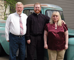 Deacon Joseph Newton poses for a picture with his parents, Our Lady of the Greenwood parishioners Larry and Caroline Newton of Greenwood, on May 22 in front of his 1956 Chevrolet pick-up truck, which he is restoring as a hobby. Deacon Newton&rsquo;s brother, Tommy, and his wife, Ashley, and their children, Joseph and Seth, will sit with his sister, Jessica Fulp, and her husband, Mike, during the ordination Mass on June 7 at SS. Peter and Paul Cathedral. (Photo by Mary Ann Wyand)