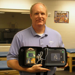 Bishop Chatard High School athletic director Mike Ford shows the Automated Electronic Defibrillator that was donated to the Indianapolis North Deanery high school by the Reviving Hearts Program. The program hopes to have the life-saving medical device at all Indiana high schools within five&nbsp;years. (Photo by John Shaughnessy)