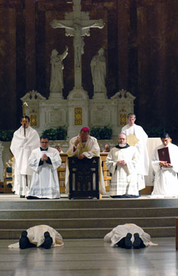 Archbishop Daniel M. Buechlein kneels in prayer on a prie dieu while, from left, deacons Joseph Newton and Aaron Jenkins lay prostrate during the praying of the litany of the saints. The two were ordained to the priesthood on June 7 at SS. Peter and Paul Cathedral in Indianapolis. Assisting Archbishop Buechlein are, from left, seminarian Benjamin Syberg, Ford Cox, the archbishop&rsquo;s administrative assistant, Benedictine Father Julian Peters, administrator pro-tem of the Cathedral Parish and seminarians Daniel Bedel and Martin Rodriguez. (Photo by Sean Gallagher)