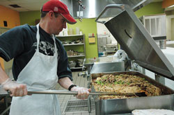 Volunteer Tim Barbour of Indianapolis stirs about 600 servings of spaghetti in a 35-gallon tilt skillet at the Second Helpings production kitchen. St. Joan of Arc parishioner Nora Spitznogle of Indianapolis, director of operations for Second Helpings, said &ldquo;everything happens on a giant scale here.&rdquo; (Photo by Mary Ann Wyand) 