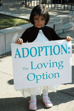 Three-year-old Iranelly Madrigal holds a pro-life sign promoting adoption in front of the SS. Peter and Paul Cathedral rectory in Indianapolis during the Central Indiana Life Chain on Oct. 5 as part of national Respect Life Sunday observances. She is the daughter of St.&nbsp;Bartholomew parishioner Rocio Sanchez of Columbus. (Photo by Mary Ann Wyand) 