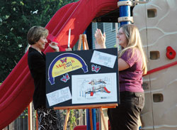 St. Joan of Arc School principal Mary Pat Sharpe of Indianapolis, left, cuts the ribbon on new playground equipment with help from Suzi Abell, right, director of curriculum and the art teacher, during a Sept. 22 dedication ceremony at the Indianapolis North Deanery parish. The school&rsquo;s Monarch Parc was dedicated in Sharpe&rsquo;s honor for six&nbsp;years of exceptional service to the students. (Photo by Mary Ann Wyand) 