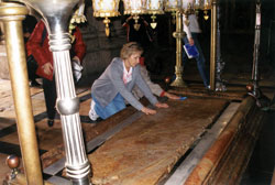 Mary Jo Thomas Day, director of religious education at St. Monica Parish in Indianapolis, kneels down in&nbsp;the Church of the Holy Sepulchre in Jerusalem and places her hands on the stone of unction where Jesus was prepared for burial. She participated in a pilgrimage to the Holy Land with St. Monica parishioners last April as part of a three-month sabbatical. Thomas Day and her family are members of Holy Cross Parish in Indianapolis. (Submitted photo) 