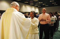 Dominican Sister Diana Dorlorita, a catechetical minister in Curacao in the Netherlands Antilles, receives Communion on March 25 from Msgr. Joseph F. Schaedel, vicar general, during the opening Mass of the National Catholic Educational Association&rsquo;s annual convention at the Indiana Convention Center in Indianapolis. (File photo by Sean Gallagher) 