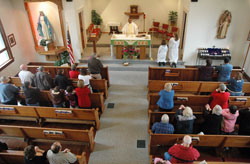 Members of Holy Rosary Parish in Seelyville kneel in prayer while Father Dominic Chukwudi, administrator, prays the eucharistic prayer during a Nov. 9 Mass at the parish&rsquo;s church. Archbishop Daniel M. Buechlein was the primary celebrant of an Oct. 11 Mass at the parish that celebrated the 100th anniversary of its founding. (Photo by Sean Gallagher) 