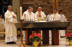 Archbishop Daniel M. Buechlein celebrates the Mass of Dedication for the new St. Malachy Church in Brownsburg on Dec. 16 as Msgr.&nbsp;Joseph F. Schaedel, vicar general, center, and Father Daniel Staublin, pastor, right, assist as concelebrants. Deacon Daniel Collier stands at the left of the altar. Jason Kippenbrock, back left, and Scott Kelley were among the altar servers. Priests with connections to St. Malachy Parish and pastors of other Indianapolis West Deanery parishes also concelebrated the historic Mass. (Photo by Mary Ann Wyand) 