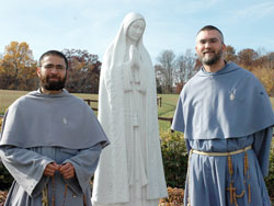 Franciscans of the Immaculate Father Jacinto Mary Chapin, left, vocation director, and Father Elias Mary Mills, father guardian of the Marian Friary of Our Lady Coredemptrix, stand beside a statue of Mary on Nov. 6 at Mother of the Redeemer Retreat Center near Bloomington. Franciscan Father Joachim Mary Mudd and five Franciscan Sisters of the Immaculate also minister at the retreat center. The friar&rsquo;s order was founded in Italy in 1970 and granted pontifical status in 1998. The sisters&rsquo; order was founded in 1985. (Photo by Mary Ann Wyand) 
