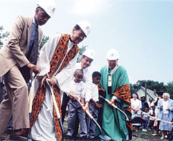 Archbishop Daniel M. Buechlein breaks ground for the new Holy Angels School and Parish Center in Indianapolis with help from Father Clarence Waldon, then-Mayor Steve Goldsmith, students and others involved in the project. The new school opened on Aug. 30, 1999. It was the first new inner-city school built in the United States in 40 years and was made possible by the archdiocesan Making&nbsp;a Difference campaign. (Archive photo) 