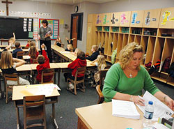 Leah McCool, right, serves as a volunteer teacher&rsquo;s aide in the first-grade classroom at St. Michael School in Brookville. In the background, St. Michael School first-grade teacher Melanie Back asks her students a question on Jan. 7. (Photo by Sean Gallagher) 
