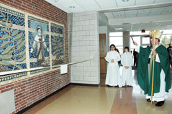 Archbishop Daniel M. Buechlein blesses a tile mosaic of St. Lawrence on Feb. 15 in the new entrance of Father Conen Hall at St. Lawrence Parish as part of his pastoral visit to the Indianapolis North Deanery parish. St. Lawrence School art teacher Allison Altherr, project volunteer Anna Marie Burrell and other parishioners helped the students with the project. Archbishop&nbsp;Buechlein was also the main celebrant at a Mass before the blessing ceremony. (Photos by Mary Ann Wyand) 