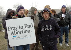 St. Malachy parishioners Zachary Duckett, left, and Owen Duckett of Brownsburg pray in front of the Planned Parenthood abortion center in Indianapolis on Feb. 22 as part of the &ldquo;40 Days for Life&rdquo; spring prayer campaign. The brothers were among a number of youths who prayed the rosary for an end to abortion. (Photo by Mary Ann Wyand) 