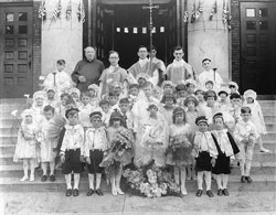 Father Augustine Sansone, fourth from left in the back row, stands on the steps of Our Lady of the Most Holy Rosary Church in Indianapolis after his first&nbsp;Mass on May 26, 1929. The parish&rsquo;s founding pastor, Father Marino Priori, stands second from left in the back row. (Archive photo) 