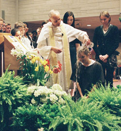 Dominican Father Robert Keller, pastor of the St. Paul Catholic Center in Bloomington, baptizes Hillary Brooks, a senior at Indiana University in Bloomington, during the parish&rsquo;s Easter Vigil on April 11. (Submitted photo) 
