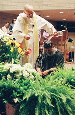 Dominican Father Robert Keller, pastor of the St. Paul Catholic Center in Bloomington, baptizes William Valentine during his parish&rsquo;s Easter Vigil on April 11. (Submitted photo) 