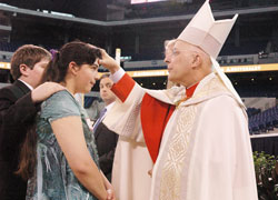 Cardinal Francis E. George of Chicago confirms Alisha Webber, a member of Holy Family Parish in Oldenburg, during the May&nbsp;3 Mass at Lucas Oil Stadium in Indianapolis that celebrated the 175th anniversary of the Archdiocese of Indianapolis. (Photo by Sean Gallagher) 