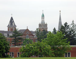 The spires of Holy Family Church and the motherhouse of the Congregation of the Sisters of the Third Order of St. Francis rise up over the trees of historic Oldenburg. The southeastern Indiana town serves as the starting and ending point of the two loops of the &ldquo;Vatican Ride&rdquo; in which bicyclists can view several parish churches in Franklin County. (File photo by Mary Ann Wyand) 