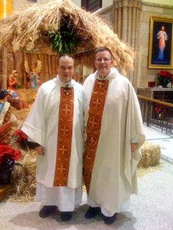 On Christmas Eve in 2008, Deacon Peter Marshall, left, poses for a photograph at St. Mary Church in Indianapolis with Father Michael O&rsquo;Mara, pastor, near a Nativity scene. Deacon Marshall was a member of St. Mary Parish when he entered the seminary. (Submitted photo) 