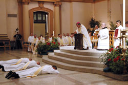 Archbishop Daniel M. Buechlein and concelebrating priests kneel in prayer for the litany of the saints with the assembly as Deacons Jeremy Gries, from left, John Hollowell and Peter&nbsp;Marshall lay prostrate on the marble during the ordination Mass on June 6 at SS. Peter and Paul Cathedral in Indianapolis. Benedictine Father Julian Peters, administrator pro-tem of Cathedral Parish and the master of ceremonies, and seminarian Martin Rodriguez kneel to the right of the archbishop. (Photo by Mary Ann Wyand) 