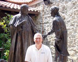 To mark his 25 years at Roncalli High School in Indianapolis, principal Chuck Weisenbach traveled to Italy this summer to learn more about the life of Angelo Roncalli&mdash;the peasant boy who grew up to become Pope John XXIII. Weisenbach stands near a bronzed statue of Pope John XXIII that was erected in front of the home where Angelo Roncalli was born. (Submitted photo)