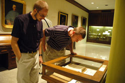 Seminarians Phillip Rahman, left, and David Proctor peer into a display case in the Old Cathedral Library in Vincennes that houses many of the books of Bishop Brut&eacute; and early documents of the Diocese of Vincennes, which later became the Archdiocese of Indianapolis. (Photo by Sean Gallagher)