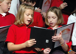 St. Jude School fourth-graders Samantha Curtis, left, and Alexandra Lawson of Indianapolis sing during the opening session of the &ldquo;Spreading Hope in Neighborhoods Everywhere&rdquo; conference on Oct. 1 at Lucas Oil Stadium in Indianapolis. In their workshop, archdiocesan youth and young adult ministry leaders Mary Schaffner and Kay&nbsp;Scoville urged parish leaders to connect the Eucharist to works of social ministry. (Photo by Mary Ann Wyand) 