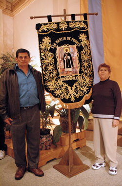 St. Mary parishioner Jaime Torpoco of Indianapolis, left,&nbsp;who is a native of Peru, and his mother, Jobita&nbsp;Oscorima of Lima, Peru, pose for a photograph beside&nbsp;an ornate, handmade banner honoring St. Martin de Porres after the saint&rsquo;s feast day Mass on Nov. 3 at SS.&nbsp;Peter and Paul Cathedral in Indianapolis. The religious banner was created by one of their relatives as well as several Peruvian youths in Lima. (Photo by Mary Ann Wyand)