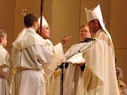 Archbishop Charles J. Chaput of Denver speaks to Bishop Paul D. Etienne after the newly ordained bishop of Cheyenne, Wyo., placed a miter on his head for the first time. Archbishop Chaput is assisted by, from left, altar server Zach Flanagan, a member of Our Lady of Perpetual Help Parish in New&nbsp;Albany, and Deacon Charles Parker of the Denver Archdiocese. (Photo by Sean Gallagher)