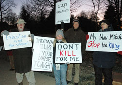 Amnesty International members Jared Carter of Indianapolis, from left, Ashley Kincaid of Avon, Michael Hartt of Indianapolis and Karen Burkhart, the Indiana death penalty abolition coordinator for Amnesty International and member of St. Susanna Parish in Plainfield, hold signs on Dec. 10 in front of the Governor&rsquo;s Residence in Indianapolis indicating their opposition to capital punishment and the execution of Matthew Wrinkles. (Photo by Mary Ann Wyand)