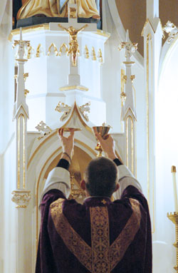 Father Jonathan Meyer, the pastor of St. Anne and St. Joseph parishes in Jennings&nbsp;County and St. Mary Parish in North Vernon, elevates the Body and Blood of Christ during a March 29, 2009, Mass at St. Anne Church. Thieves broke into St.&nbsp;Anne Church during the night on Dec. 27 or the early morning hours of Dec. 28 and took a 700-pound safe containing antique gold sacred vessels. (File photo by Mary Ann Wyand)