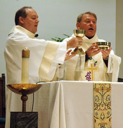 Deacon David Henn and Msgr. Mark Svarczkopf, pastor of Our Lady of the Greenwood Parish in Greenwood, elevate the chalice and paten at the end of the eucharistic prayer during a Nov. 11 Mass at the parish&rsquo;s church. (Photo by Sean Gallagher)