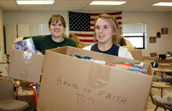 Catherine Aubrey, left, and Hadley Anderson, juniors at Our Lady of Providence Jr./Sr. High School in Clarksville, carry boxes of toys on Dec. 11, 2009, that were donated to the Marine Foundation Toys for Tots to the school&rsquo;s lobby. The toy drive at Providence was organized by the school&rsquo;s House of Justice and House of Faith. Students from all four grade levels in the senior high school are arranged in eight houses in a new student leadership model launched last fall at Providence. (Submitted photo)